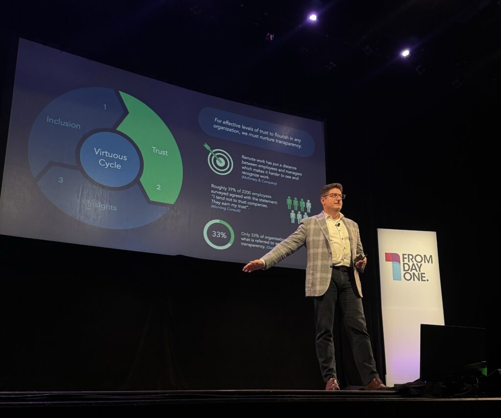 Man on stage with presentation displayed on large screen