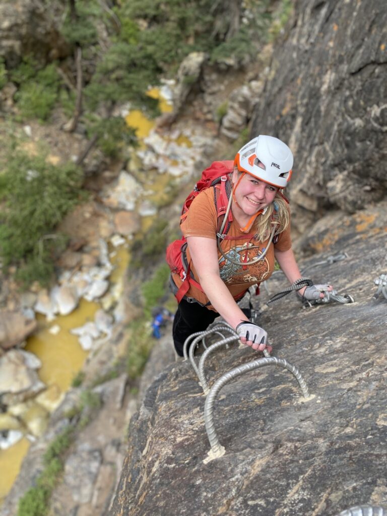 Woman climbing side of mountain for employee spotlight feature