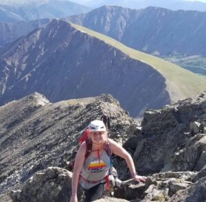 Woman at the top of a mountain with view behind her