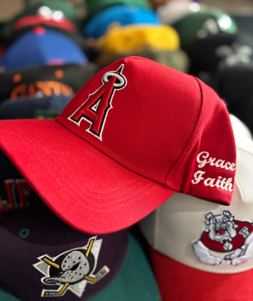 Baseball caps stacked in a row with red Angels one on top for employee spotlight
